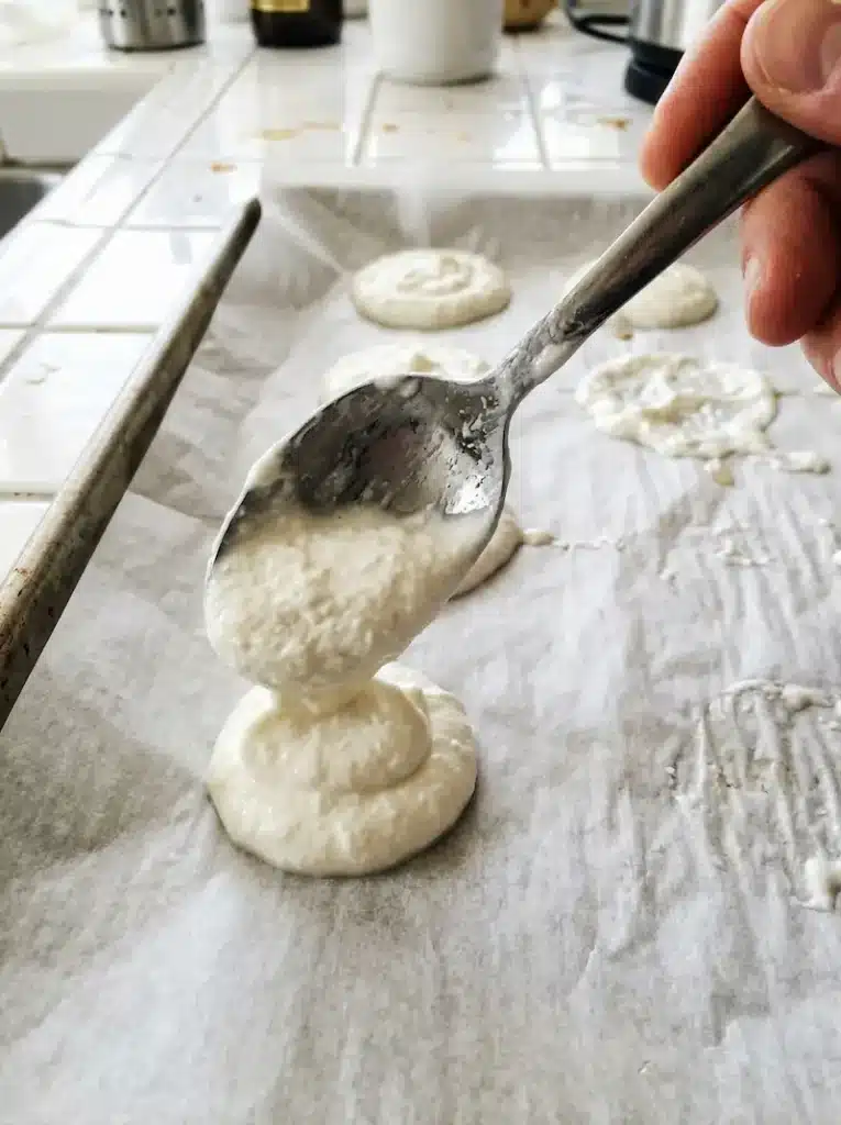 Spooning Greek Yogurt onto Parchment for Yogurt Clusters spooning thick Greek yogurt onto parchment paper to make frozen yogurt clusters