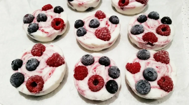 frozen yogurt clusters with blueberries and raspberries on white parchment paper
